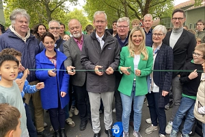 1 Leopold-Lucas-Straße Eine Gruppe von Personen stehen hinter einem Band mit Scheren und lächeln in die Kamera.