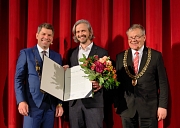 Oberbürgermeister Dr. Thomas Spies, der Präsident der Philipps-Universität, Prof. Dr. Thomas Nauss, und der diesjährige Kamerapreisträger, Sturla Brandth Grøvlen, stehen vor der Kinoleinwand im Cineplex.