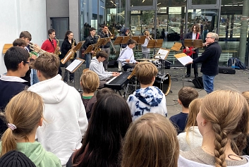 Hinter Kinderköpfen ist eine Schulband zu sehen, die zur Feier auftritt.