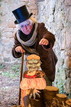 Zu sehen ist eine mit Zylinder, Mantel und Gehstock verkleidete Person, die hinter einer Ungeheuer-Figur steht. © Nadine Schrey, i. A. d. Stadt Marburg
