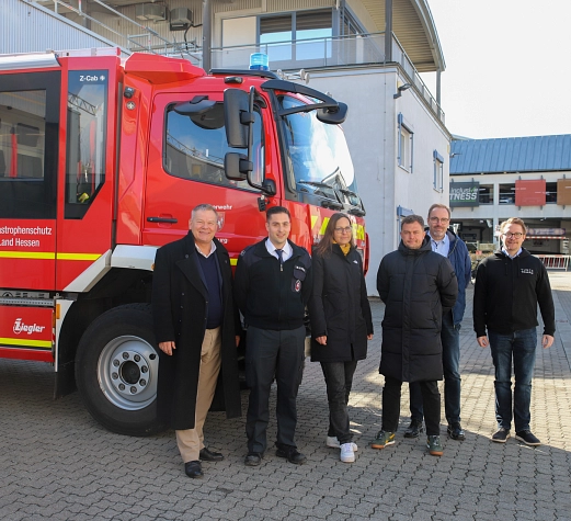 Sechs Personen stehen vor einem Feuerwehrauto.