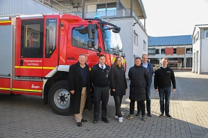 Ampelschaltung FFW. Sechs Personen stehen vor einem Feuerwehrauto.