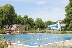 Schwimmer im Sportbecken ziehen ihre Bahnen. Im Hintergrund die Halle und die Rutsche. © Universitätsstadt Marburg - Rolf Klinge