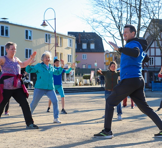 Auftakt Offene Bewegungsangebote Mehrere Personen machen Sport auf einem Platz.