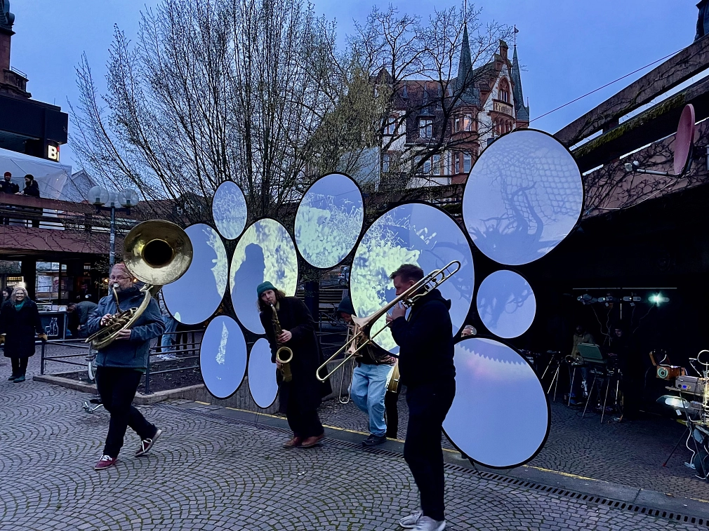 Die Musikgruppe "The Dorf" steht auf dem Rudolphsplatz und macht Musik. Auf dem Platz befinden sich Lichtinstallationen und Projektionen.&nbsp;&copy;&nbsp;Monika Bunk, Stadt Marburg