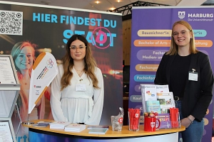 ausbildungsmesse_foto_stefanie_ingwersen_stadt_marburg__ausschnitt_1__.jpg Zwei Frauen stehen an einem Messestand der Stadt Marburg.