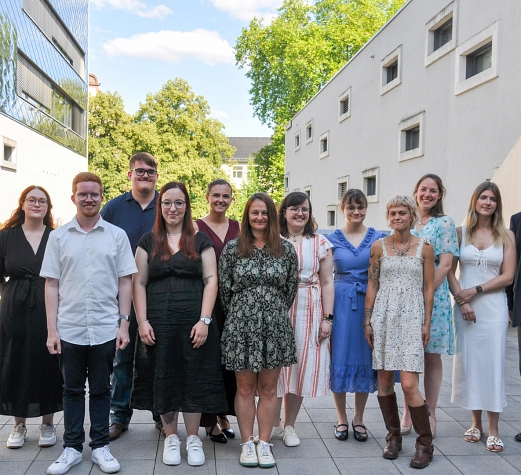Azubi_Abschlussfeier Auf dem Bild sieht man 14 Personen, gemischt aus Damen und Herren, die alle glücklich und zufrieden in die Kamera schauen.