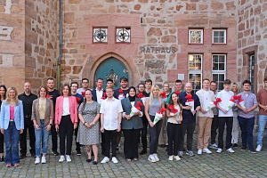 Azubis 2024 Das Bild zeigt ein Gruppenbild mit den neuen Azubis und deren Willkommenspräsenten vor dem Marburger Rathaus.