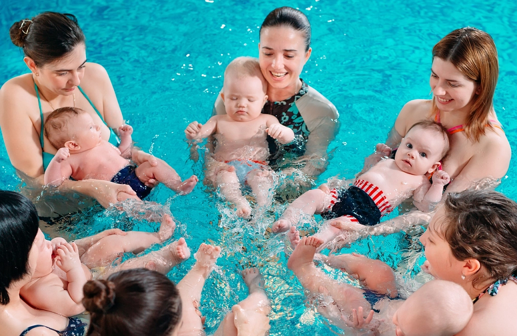 Babyschwimmen im Hallenbad Wehrda Frauen halten im Wasser ihre Baby vor ihrem Körper in ihren Armen, sodass die Baby mit den Beinen planschen können. © iStock/davit85