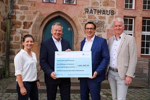 Vier Personen stehen mit dem Bescheid vor dem Rathaus.