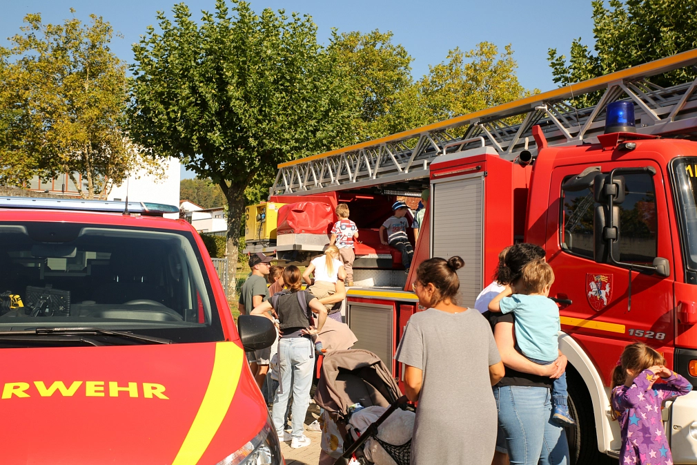Das Bild zeigt mehrere Personen vor verschiedenen Arten von Feuerwehrfahrzeugen.