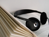 Kopfhörer liegt auf einem aufgeschlagenem Buch © Stadtbücherei Marburg