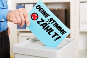 Einwurf eines Stimmzettels mit de Aufschrift "Deine Stimme zählt" in eine Wahlurne
