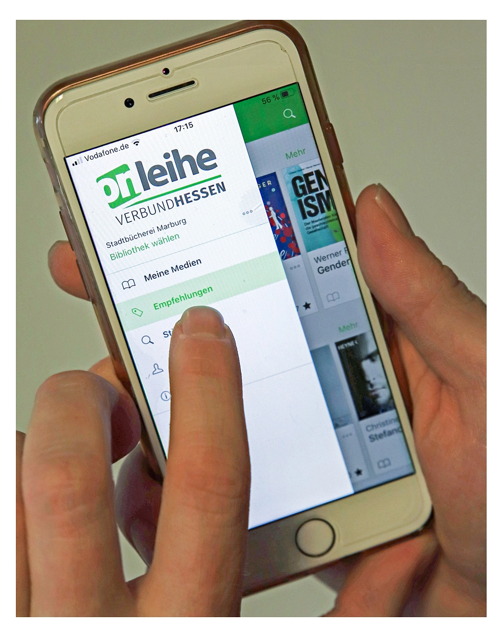 Eine Hand hält ein Smartphone in der Hand. Der Bildschirm zeigt die Startseite der "Onleihe". Ein Finger klickt auf die Schaltfläche "Empfehlungen".&nbsp;&copy;&nbsp;Simone Batz, Stadt Marburg