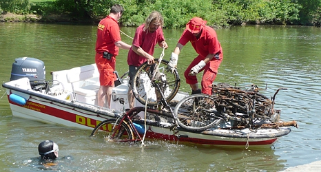 Das Foto zeigt Freiwillige der DLRG, die ein Fahrrad aus der Lahn in ein Motorboot hieven. © DBM, Sonja Stender