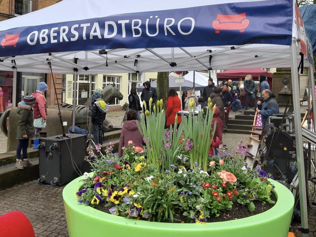 Ein Pavillon mit der Aufschrift "Oberstadtbüro" am Fuße des Steinwegs, davor steht ein großer, grüner bepflanzter Blumenkübel.