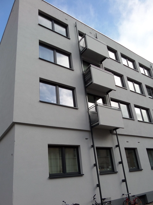 Hausfassade mit mehreren, kaum sichtbaren Einflugritzen für Fledermäuse. Die Fledermausquartiere sind unter dem Putz.