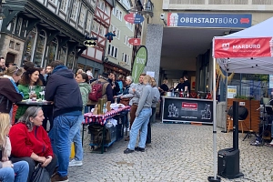 Der „Afterwork Oberstadt“ im Mai 2025: Viele Besucher*innen vor dem Oberstadtbüro am Heumarkt. Ein Musiker spielt auf seiner Gitarre.
