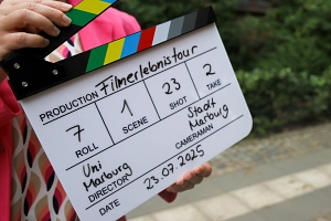 Filmerlebnistour Eine Person hält eine Regieklappe in den Händen.