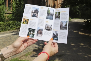 Filmerlebnistour_Flyer_Alter botanischer Garten Im Alten botanischen Garten: Zwei Hände halten den aufgeklappten Flyer zur Filmerlebnistour.