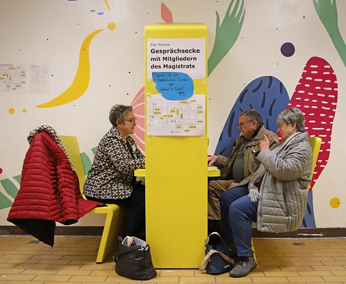 Drei Personen sitzen an einem Tisch und unterhalten sich.