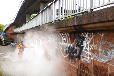 In einer Wolke aus Wasserdampf verschwindet nicht nur der Mitarbeiter des DBM, sondern auch die Graffiti. © Sonja Stender, Dienstleistungsbetrieb der Stadt Marburg
