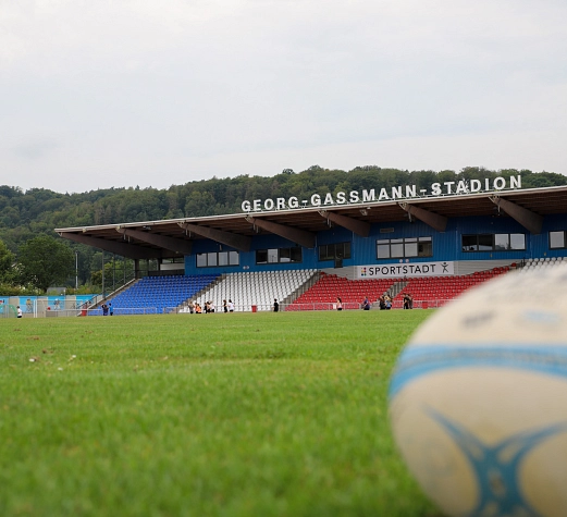 Georg-Gaßmann-Stadion_Foto Dennis Siepmann, Stadt Marburg Es ist ein Ball auf einem Rasen zu sehen. Im Hintergrund erkennt man das Georg- Gaßmann-Stadion.