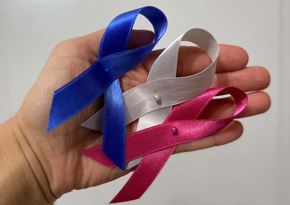 Gesunde Stadt: Krebs-Vorsorge und Krebs-Schleifen Eine Hand hält drei Bänder, die zu Schleifen gelegt sind: eine blaue Schleife als Symbol für Prostatakrebs, eine hellgraue Schleife als Symbol für Hirntumore und Weltkrebstag sowie eine pinke Schleife als Symbol für Brustkrebs. © Simone Batz, Stadt Marburg