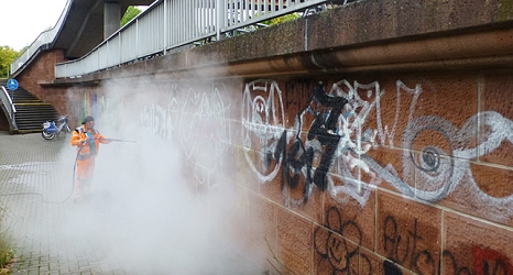 Das Foto zeigt einen Mitarbeiter des DBM bei der Beseitigung von Graffiti mit einem Dampfstrahler. © DBM, Sonja Stender