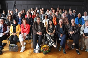 Gruppe_10 Jahre Portal Eine Gruppe von Menschen sitzt in einem Raum auf Stühlen.