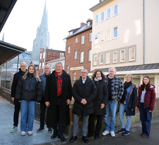 Gruppe_Zukunft Innenstadt Eine Gruppe von Menschen steht in einer Straße. Im Hintergrund ist ein Kirchturm zu sehen.