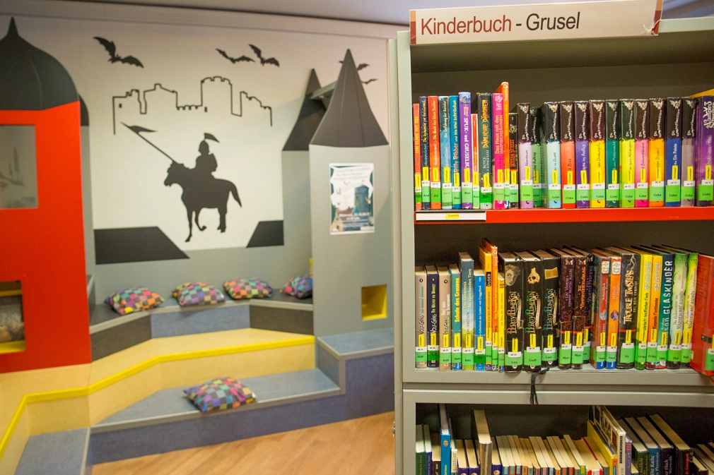 Links im Bild ist die "Leseburg" in der Kinderbücherei der Stadtbücherei zu sehen. Rechts davor steht ein Bücherregal mit Kinderbüchern. Die Aufschrift des Regals lautet "Kinderbuch-Grusel"&nbsp;&copy;&nbsp;Patricia Grähling, Stadt Marburg