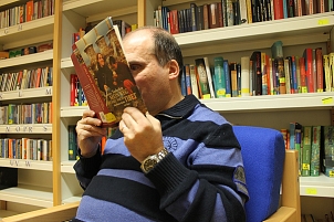 Ein Mann sitz in einem Sessel und hält ein aufgeschlagenes Buch direkt vor die Augen und versucht zu lesen. © blista / Troltenier
