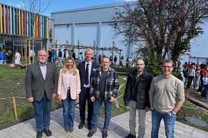 Innenhof Philippinium Es steht eine Gruppe von Menschen auf einem Schulhof und lächelt zur Kamera.