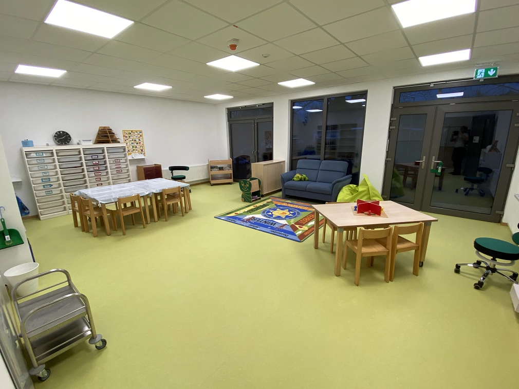 Einer der Räume in dem Interimsbau für die Kita Reinhardswaldstraße: Tische und Stühle für Kinder, ein Regal an der Wand, ein kleines Sofa am Fenster, rollbare Kleinmöbel und Drehstühle.&nbsp;&copy;&nbsp;Universitätsstadt Marburg