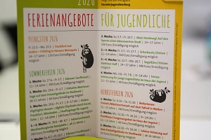 Jugendförderung_Ferienprogramm Ein Türschild steht auf einem Tisch.