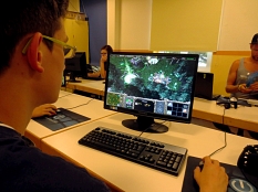 Ein Junge sitzt am Computer, im Hintergrund sind weitere Jugendliche an PCs zu sehen. © Universitätsstadt Marburg