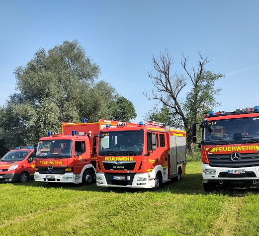Katastrophenschutzzug Vier Fahrzeuge der Feuerwehr stehen auf einer Wiese.