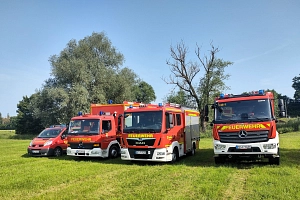 Katastrophenschutzzug Vier Fahrzeuge der Feuerwehr stehen auf einer Wiese.