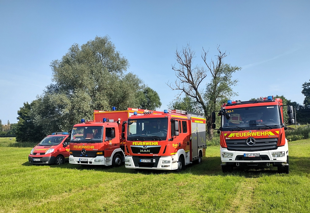 Vier Fahrzeuge der Feuerwehr stehen auf einer Wiese.