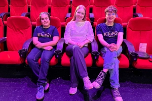 KiJuPa 2026 Drei Kinder sitzen in einem Kinosaal auf roten Kinosesseln.