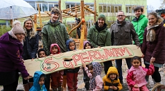 Vorschulkinder, Bürgermeisterin, Erzieherinnen und ALEA-Mitarbeiter halten gemeinsam das Schild mit der Aufschrift "Superwurm" - der Name für das selbstgebaute Klettergerüst.