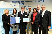 Das Marburger Team mit Gratulant/innen: Bürgermeister Wieland Stötzel (3. v. l.), Fachdienstleiterin Marion Kühn (2. v. l.) und Marburgs Klimaschutzmanager Achim Siehl (4. v. l.) nehmen den Klimaschutzpreis in Berlin entgegen.