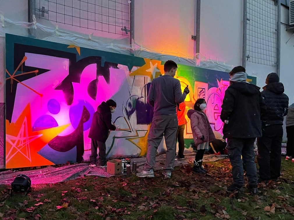 Jugendliche vor einer Wand mit Graffitis.