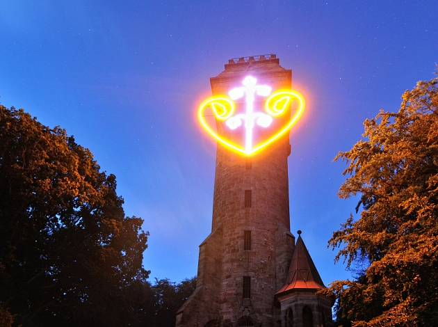 Abendaufnahme: Das Herz am Kaiser-Wilhelm-Turm leuchtet in der Dämmerung.