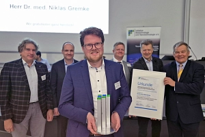 Der Preisträger steht vor einer Gruppe von fünf Personen.