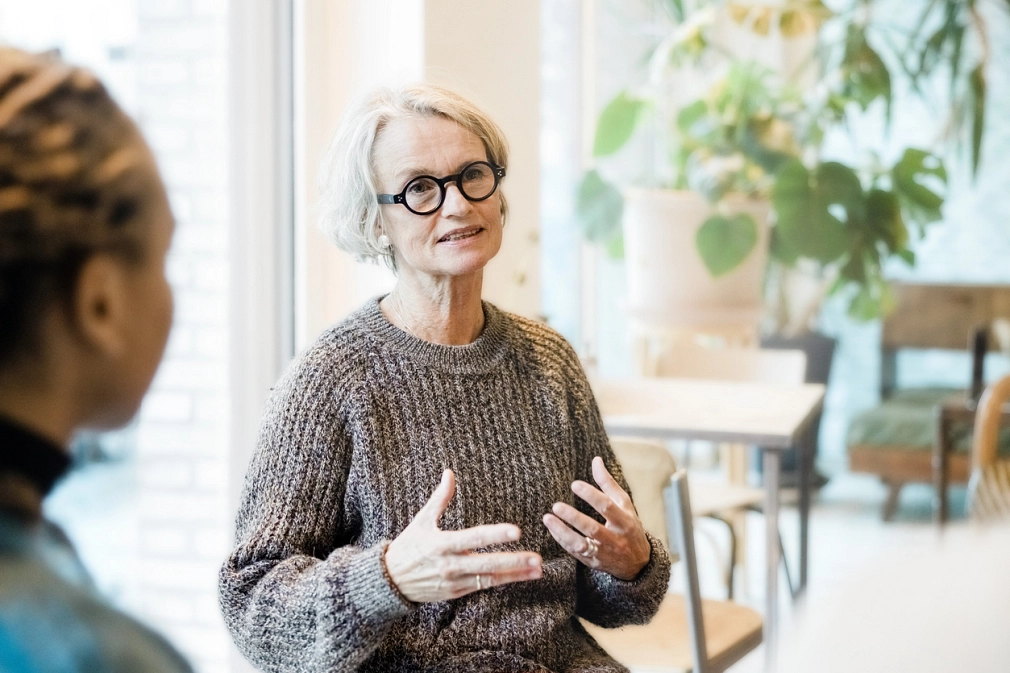Marburg_Beratung_Soziale-Hilfen_iStock-1354857441.jpg Ältere Person, die mit einer anderen Person spricht. Ihre Gestik und Mimik deuten darauf hin, dass sie etwas erklärt. © iStock/Portra