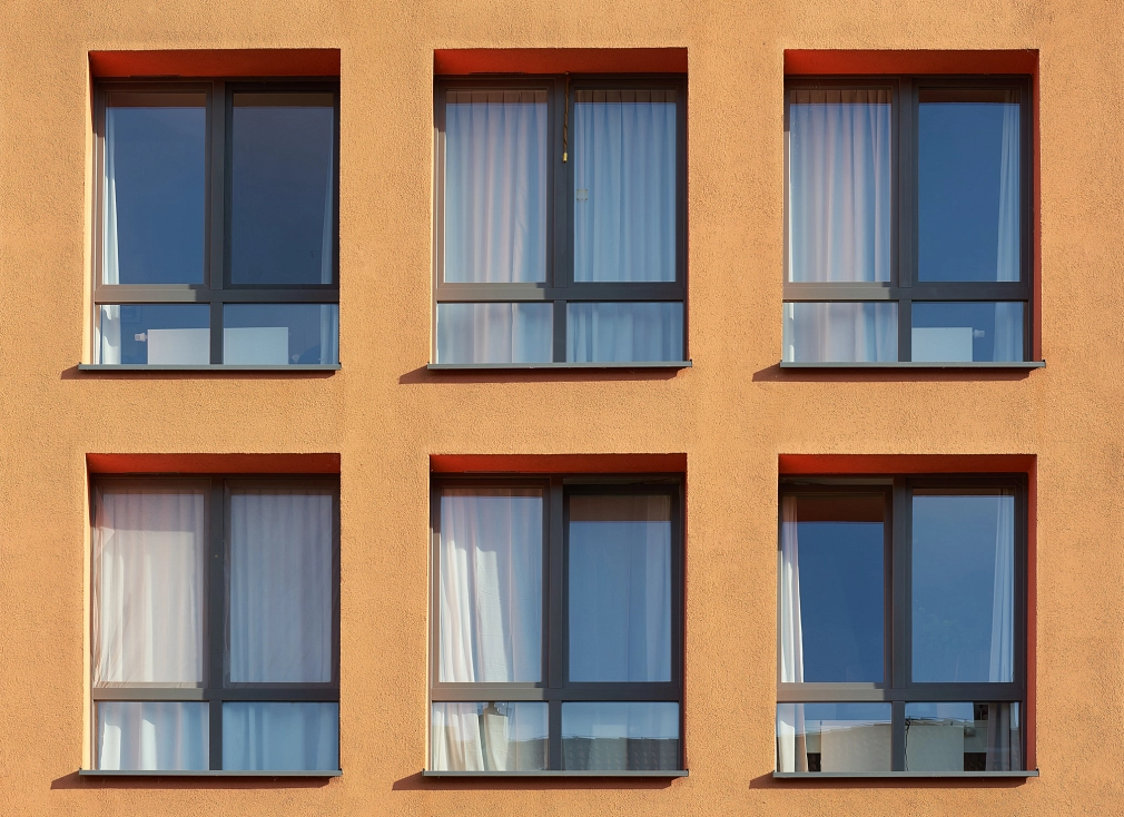 Gemeinschaftsunterkunft: Eine gelbe Hausfassade mit einheitlichen grünen Fenstern und weißen Gardinen.&nbsp;&copy;&nbsp;iStock/Heiko119
