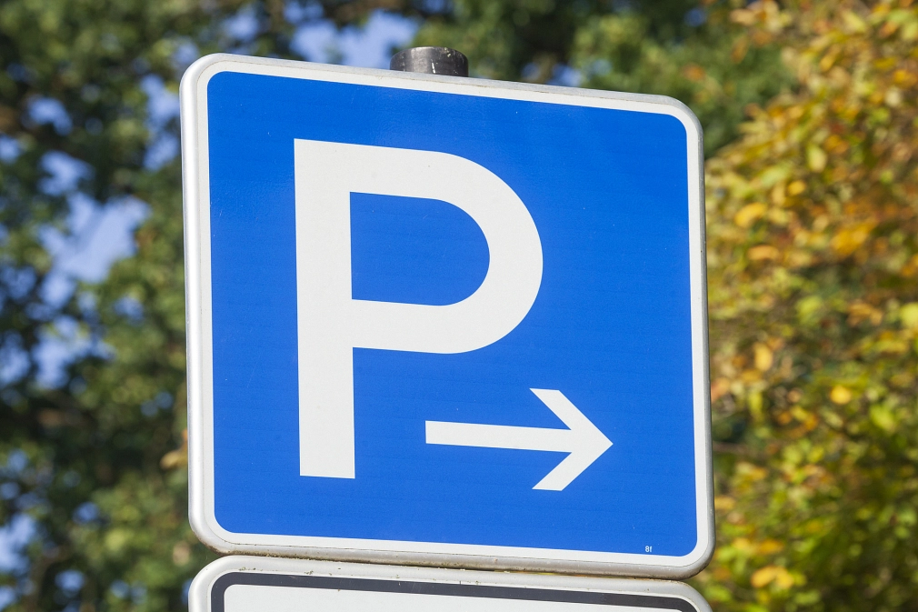 Marburg-Parken-iStock-2191833137 Hinweis auf einen Parkplatz: Ein Verkehrsschild "Parken". Im Hintergrund Stadtbäume. © iStock/Detailfoto