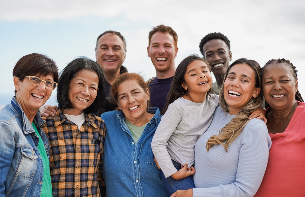 Marburg_Patenschaftsprojekt_iStock-1485140963 Zu sehen ist eine Gruppe von Menschen mehrerer Generationen, die sich umarmen und vor der Kamera lächeln. © iStock / Sabrina Bracher